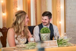 Littleton wedding photographer Lakewood Denver The Studios at Overland Crossing Santa Fe Colorado photography reception hall candid husband wife bride and groom toasts in love head table Mr. Mrs.