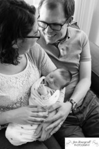 Littleton family photographer parenthood parents newborn new baby Colorado lifestyle photography in home session swaddled boy days old sleeping sleepy happy content black and white mother father