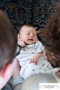 Littleton family photographer newborn new baby boy in home lifestyle Colorado photography smiles parenthood swaddled snuggled hair days old