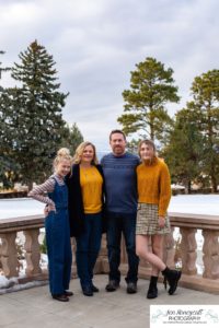 Littlleton family photographer Highlands Ranch Mansion stone building winter snow fall leaves red barn old building metal gate sisters big little girls teen teenagers foothills view at sunset