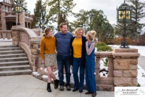 Littlleton family photographer Highlands Ranch Mansion stone building winter snow fall leaves red barn old building metal gate sisters big little girls teen teenagers foothills view at sunset