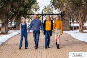 Littlleton family photographer Highlands Ranch Mansion stone building winter snow fall leaves red barn old building metal gate sisters big little girls teen teenagers foothills view at sunset