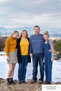 Littlleton family photographer Highlands Ranch Mansion stone building winter snow fall leaves red barn old building metal gate sisters big little girls teen teenagers foothills view at sunset