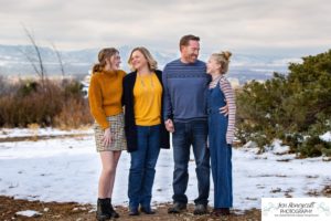 Littlleton family photographer Highlands Ranch Mansion stone building winter snow fall leaves red barn old building metal gate sisters big little girls teen teenagers foothills view at sunset