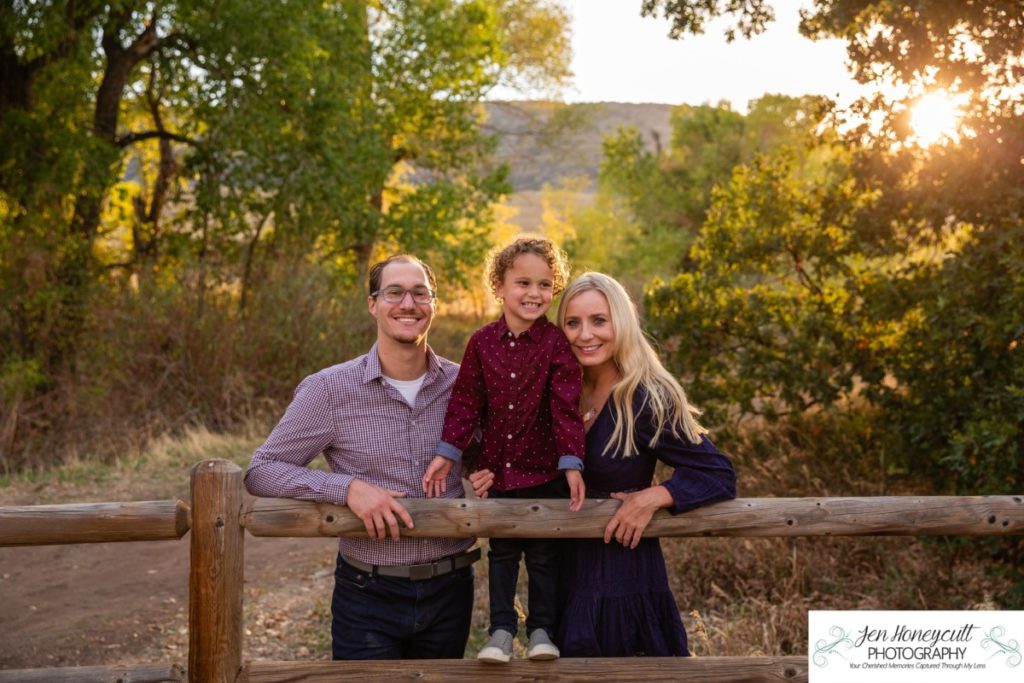 Littleton family photographer Hildebrand Ranch Colorado barn park foothills fall at sunset natural light photography mother father son little boy yellow trees twirling and kisses