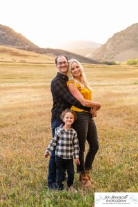 Littleton family photographer Hildebrand Ranch Colorado barn park foothills fall at sunset natural light photography mother father son little boy yellow trees twirling and kisses