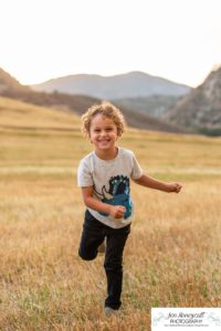 Littleton family photographer Hildebrand Ranch Colorado barn park foothills fall at sunset natural light photography mother father son little boy yellow trees twirling and kisses