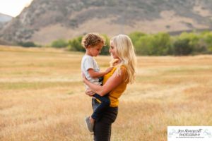 Littleton family photographer Hildebrand Ranch Colorado barn park foothills fall at sunset natural light photography mother father son little boy yellow trees twirling and kisses