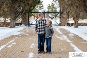 Littleton family photographer in Colorado at the Highlands Ranch Mansion in the snow boys brothers Christmas winter stone building iron gate