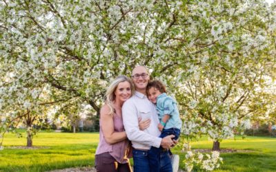 The {L} family of 3 in the crab apple tree blossoms for a spring photo session by Littleton photographer