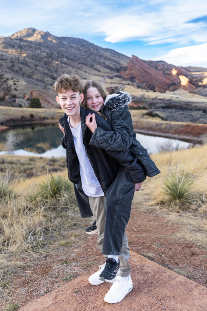 Sister on brother's back for a piggy back ride in Red Rocks.  Colorado family photographer in Morrison.