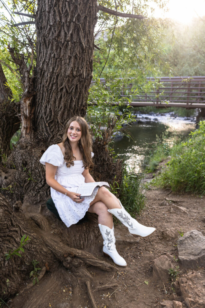 Teen reading her Bible along river in Colorado for senior photos