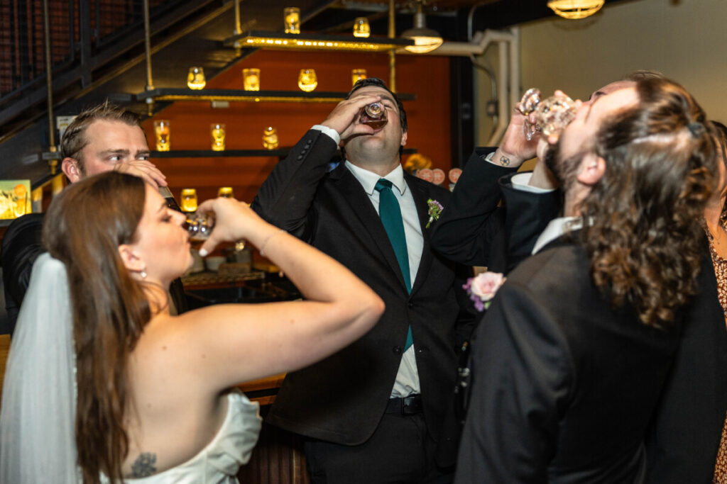 Littleton wedding photographer with bride and groom doing shots at reception